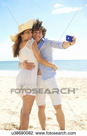 Couple self photographing with mobile phone on beach View Large Photo Image Stock Image - Couple self photographing with mobile phone on beach. Fotosearch