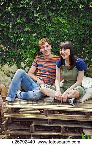 Stock Photo - Couple sitting on wooden palettes. Fotosearch