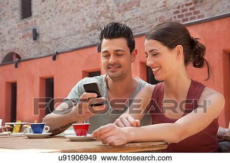 Couple using smartphone outside cafe, Florence, Tuscany, Italy View Large Photo Image Stock Photo - Couple using smartphone outside cafe, Florence, Tuscany, Italy. Fotosearch