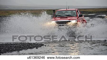 Stock Photograph - Customised SUV driving through river, Thorsmork, Iceland. Fotosearch