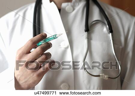 Stock Image - Doctor holding syringe. Fotosearch