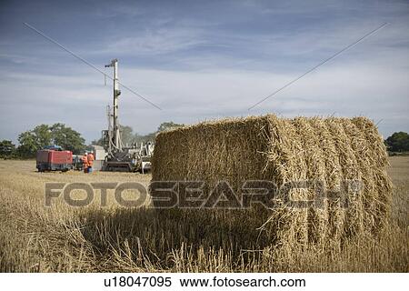 Stock Photography - Drilling rig in field with hay bale in foreground. Fotosearch