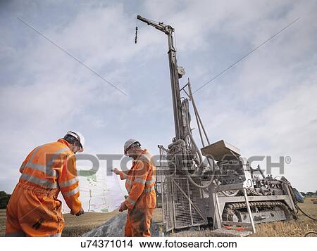 Picture - Drilling rig workers inspecting map in field. Fotosearch