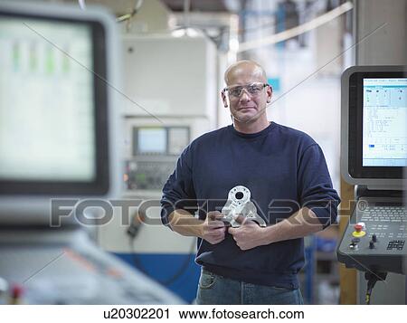Engineer holding complex metal component in factory, portrait View Large Photo Image Stock Image - Engineer holding complex metal component in factory, portrait. Fotosearch