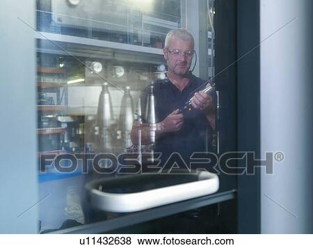 Stock Photo - Engineer inspecting lathe cutting tool in factory. Fotosearch