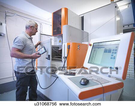 Stock Photograph - Engineer operating wire erosion machine in factory. Fotosearch