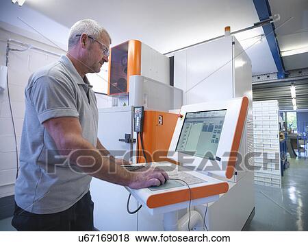 Stock Photo -  Engineer operating wire erosion machine in factory. Fotosearch