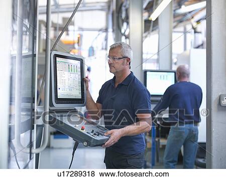 Stock Photo - Engineers at lathe controls in factory. Fotosearch