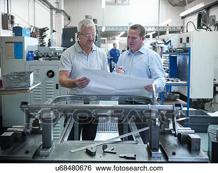Engineers inspecting plans in factory View Large Photo Image Stock Photograph - Engineers inspecting plans in factory. Fotosearch