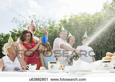 Family celebrating birthday, man opening champagne View Large Photo Image Stock Image - Family celebrating birthday, man opening champagne. Fotosearch