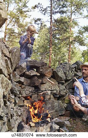Picture - Family cooking sausages over fire. Fotosearch