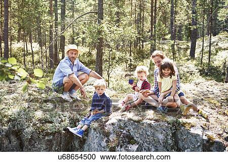 Family sitting on rocks in forest View Large Photo Image Stock Image - Family sitting on rocks in forest. Fotosearch