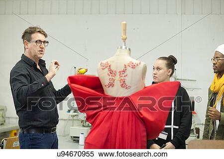 Stock Photography - Fashion design teacher assessing students work. Fotosearch