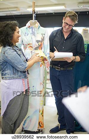 Stock Image - Fashion design teacher assessing student. Fotosearch