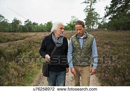 Father and adult son walking on dirt track View Large Photo Image Stock Image - Father and adult son walking on dirt track. Fotosearch