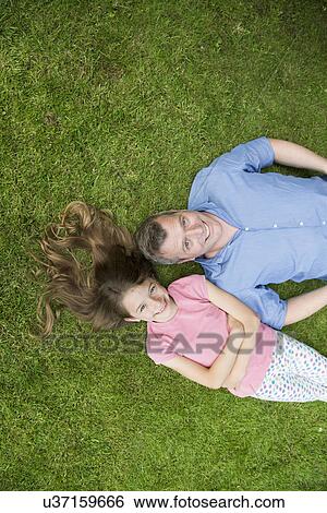 Father and daughter lying on grass View Large Photo Image Stock Photograph - Father and daughter lying on grass. Fotosearch