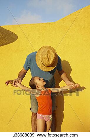 Father holding daughter's arms out by yellow wall View Large Photo Image Stock Photo - Father holding daughter's arms out by yellow wall. Fotosearch