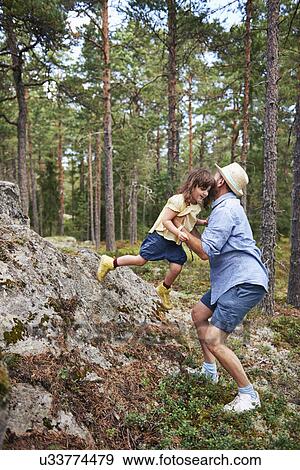 Stock Photo - Father lifting daughter from rock. Fotosearch