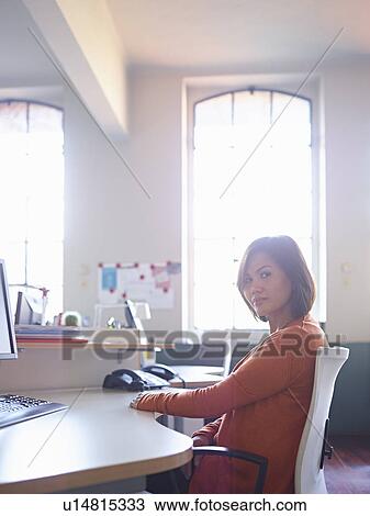 Female office worker sitting at desk View Large Photo Image Stock Image - Female office worker sitting at desk. Fotosearch