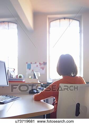 Female office worker sitting at desk, rear view View Large Photo Image Stock Image - Female office worker sitting at desk, rear view. Fotosearch