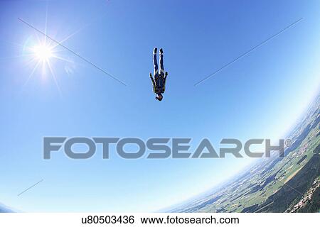 Stock Photograph - Female skydiver free falling head first above Leutkirch, Bavaria, Germany. Fotosearch