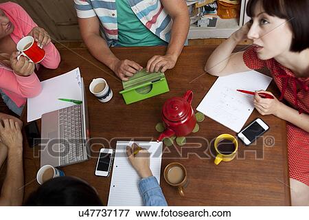 Stock Photo - Flatmates brainstorming around kitchen table. Fotosearch