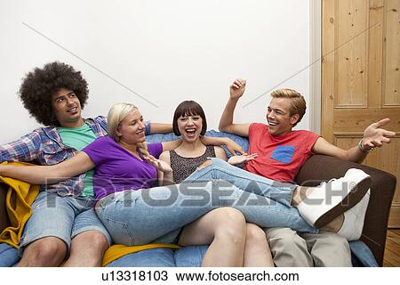 Stock Image - Flatmates reclining on sofa. Fotosearch