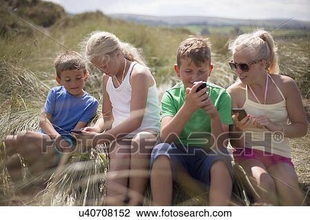 Stock Image - Four friends relaxing in dunes, Wales, UK. Fotosearch