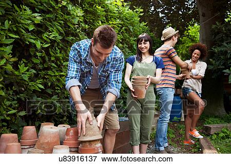 Stock Photo - Four friends stacking terracotta plant pots. Fotosearch