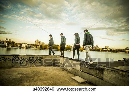 Stock Image - Four friends walking along concrete wall, Russia. Fotosearch