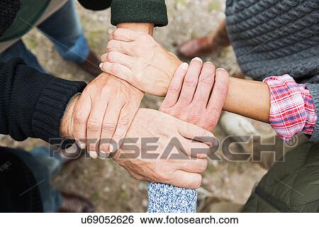 Stock Photograph - Four people touching hands, high angle. Fotosearch