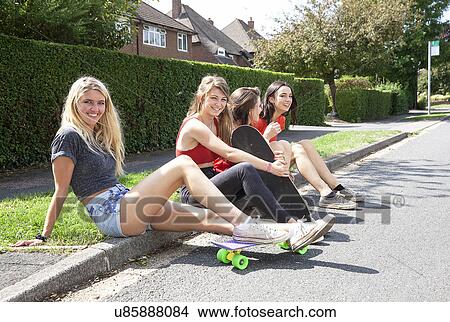 Four young women sitting on kerb View Large Photo Image Picture - Four young women sitting on kerb. Fotosearch