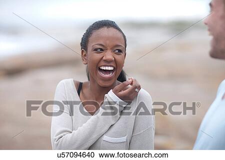 Stock Image - Friends laughing on beach. Fotosearch