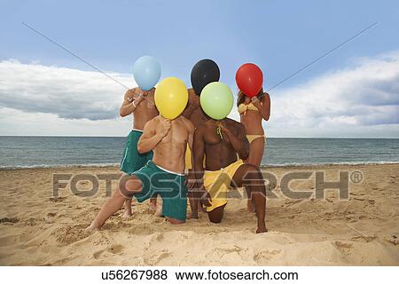 Friends on beach posing with balloon on face View Large Photo Image Stock Photo - Friends on beach posing with balloon on face. Fotosearch