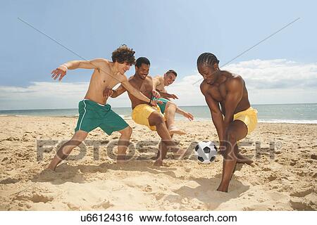 Stock Photograph - Friends playing football on beach. Fotosearch