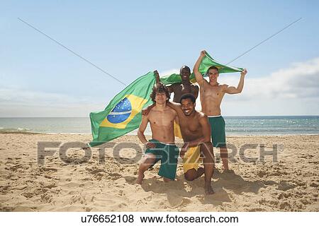 Stock Photo - Friends posing with brazilian flag on beach. Fotosearch