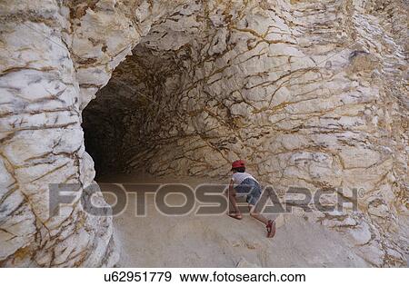 Stock Photo - Girl climbing into cave, Cabo de Gata, Almeria, Spain. Fotosearch
