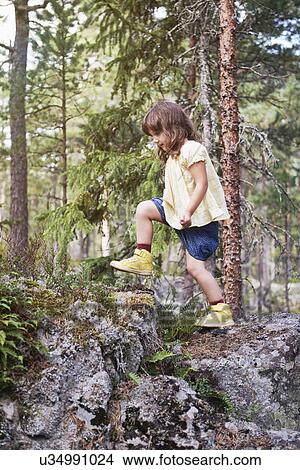 Picture - Girl climbing over rocks in forest. Fotosearch