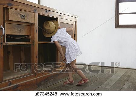 Stock Photo - Girl looking underneath cupboard. Fotosearch