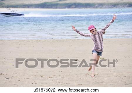 Stock Image - Girl running on beach, Daymer Bay, Cornwall, England, UK. Fotosearch
