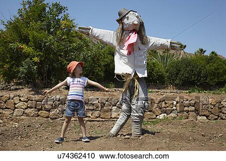 Girl standing next to scarecrow with arms out View Large Photo Image Stock Image - Girl standing next to scarecrow with arms out. Fotosearch