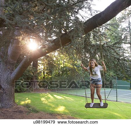 Stock Photo - Girl standing on a swing. Fotosearch