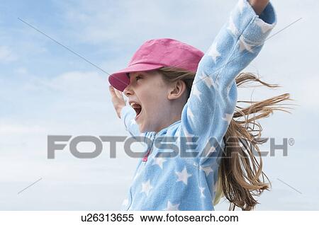 Girl wearing pink cap with arms raised in wind View Large Photo Image Stock Photography - Girl wearing pink cap with arms raised in wind. Fotosearch