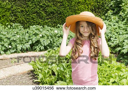Girl wearing straw hat in garden View Large Photo Image Stock Photograph - Girl wearing straw hat in garden. Fotosearch