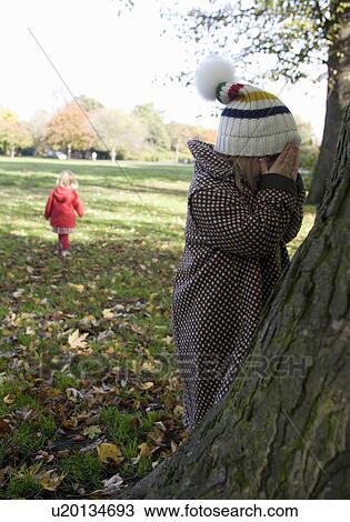 Girls playing hide and seek in park, London, England, UK View Large Photo Image Stock Image - Girls playing hide and seek in park, London, England, UK. Fotosearch