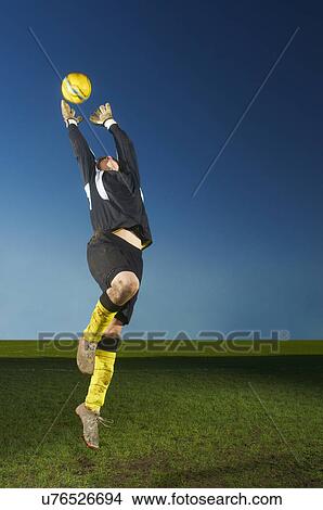 Goalkeeper jumping to catch football View Large Photo Image Picture - Goalkeeper jumping to catch football. Fotosearch