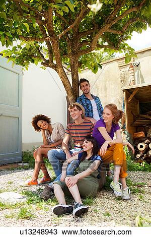 Group of friends sitting under tree View Large Photo Image Stock Image - Group of friends sitting under tree. Fotosearch