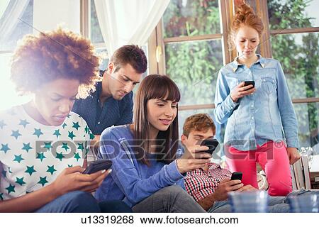Stock Photo - Group of friends using smartphones. Fotosearch