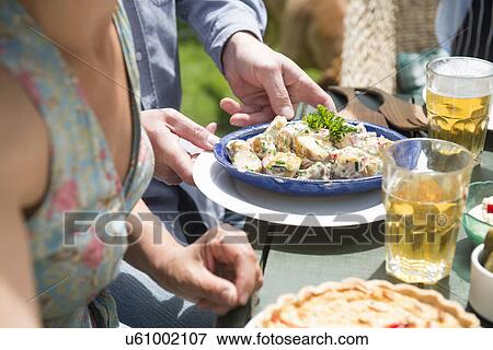 Stock Photo - Group of people with food and beer, close up. Fotosearch