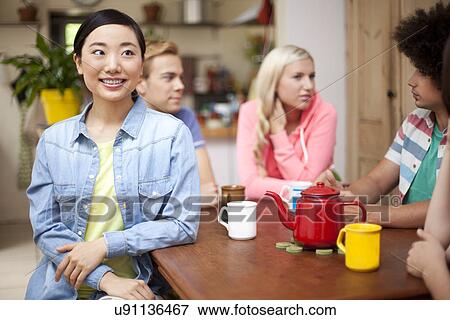 Group of young adult friends around kitchen table View Large Photo Image Stock Photo - Group of young adult friends around kitchen table. Fotosearch